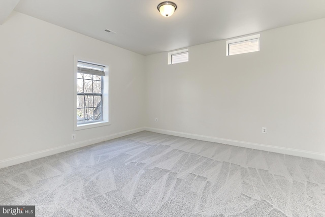 spare room with a wealth of natural light, light carpet, visible vents, and baseboards