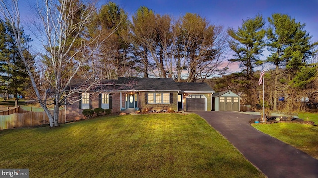 ranch-style home featuring a front yard, fence, a garage, aphalt driveway, and brick siding