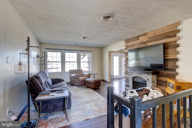 living room with visible vents, dark wood-type flooring, a textured ceiling, a fireplace, and baseboards