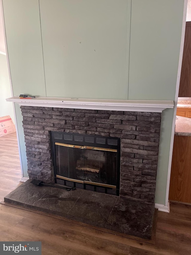 interior details featuring a stone fireplace and wood finished floors