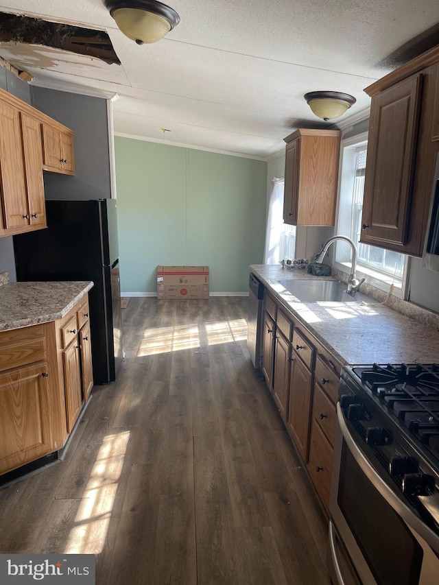 kitchen with dark wood-style flooring, crown molding, stainless steel appliances, a sink, and baseboards