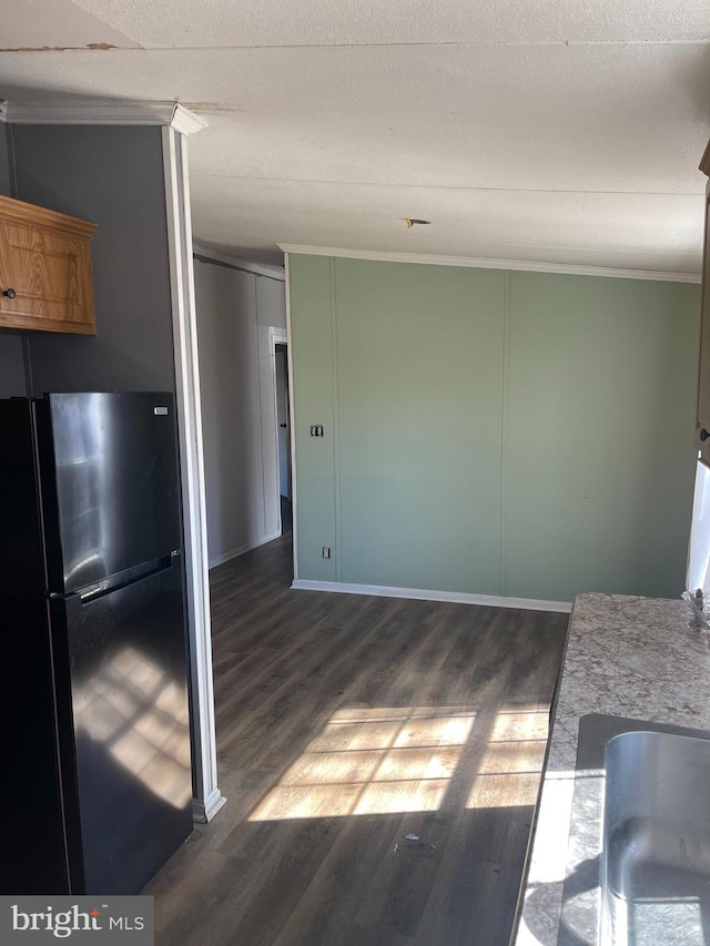 kitchen with crown molding, dark wood-type flooring, and freestanding refrigerator