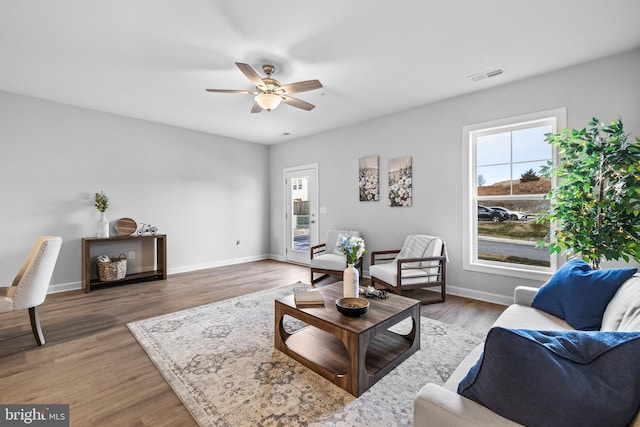 living room with visible vents, ceiling fan, baseboards, and wood finished floors