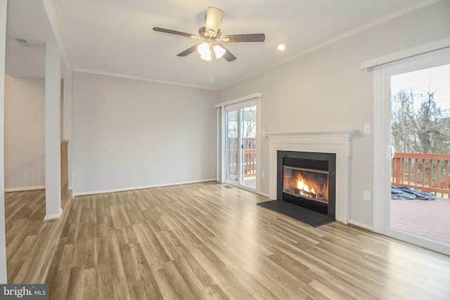 unfurnished living room with baseboards, wood finished floors, a fireplace with flush hearth, and crown molding