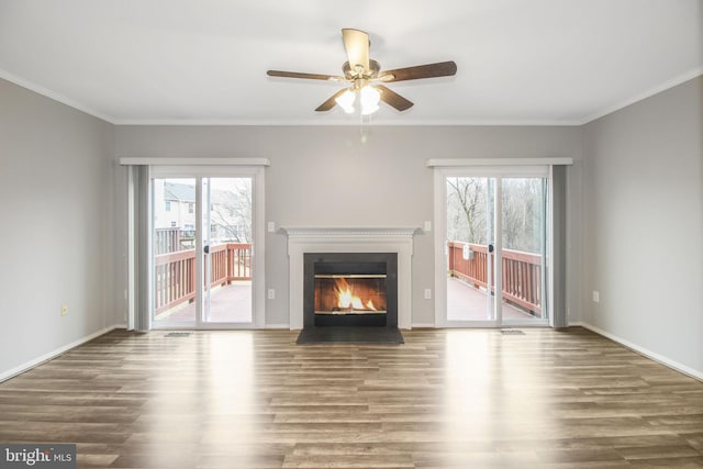 unfurnished living room featuring baseboards, wood finished floors, a fireplace with flush hearth, and crown molding