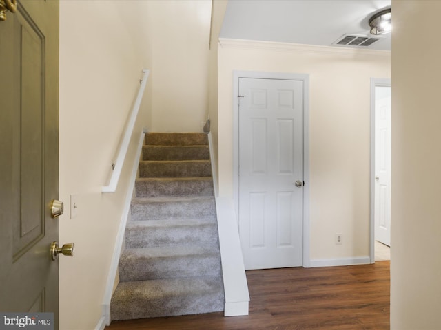 stairs featuring baseboards, visible vents, wood finished floors, and ornamental molding