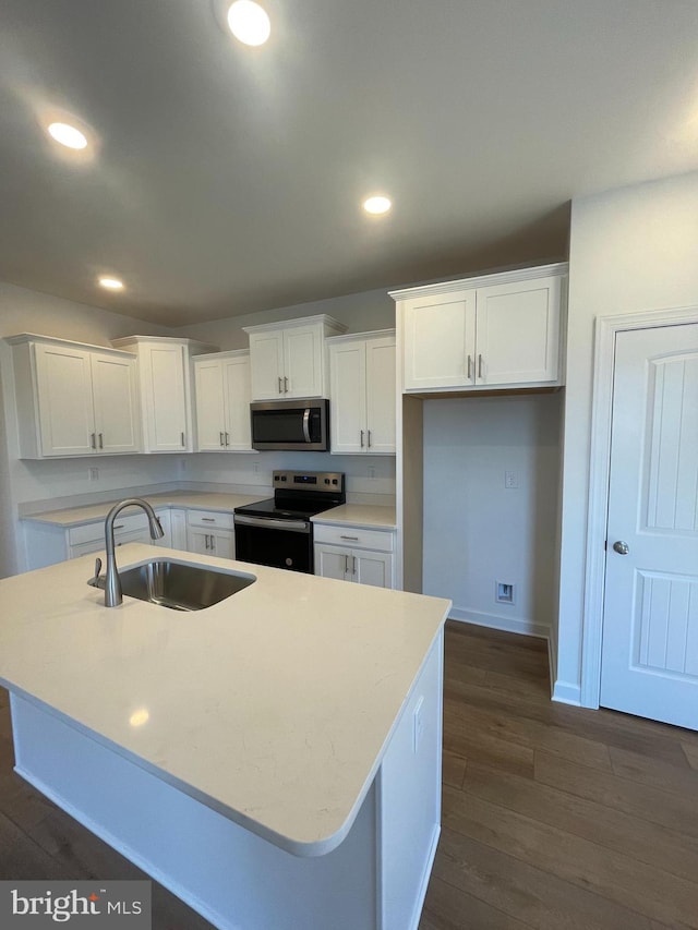 kitchen featuring stainless steel appliances, dark wood-style flooring, white cabinets, and a sink