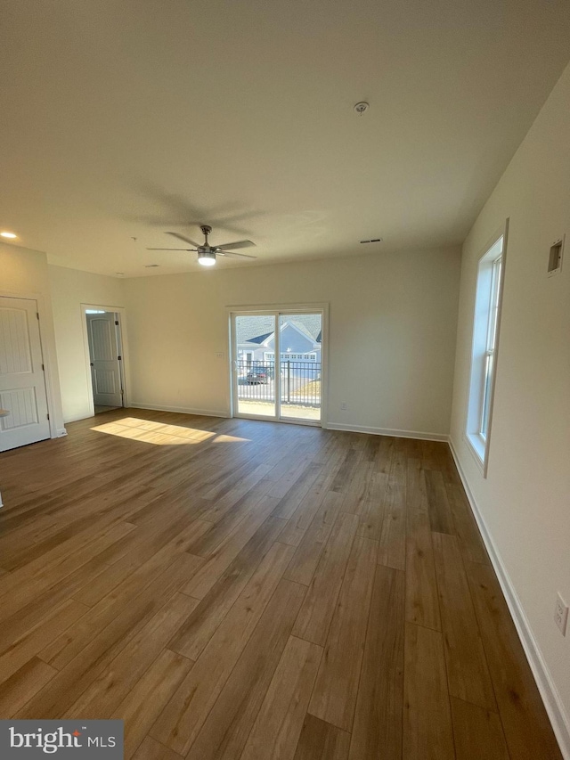 unfurnished living room with ceiling fan, baseboards, and wood finished floors