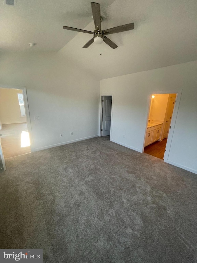 unfurnished bedroom featuring lofted ceiling, baseboards, and dark colored carpet