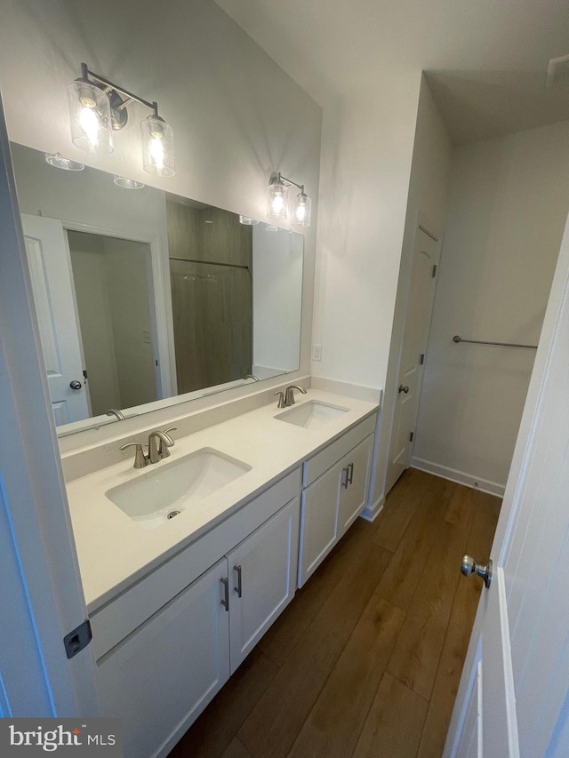 bathroom with double vanity, a sink, and wood finished floors