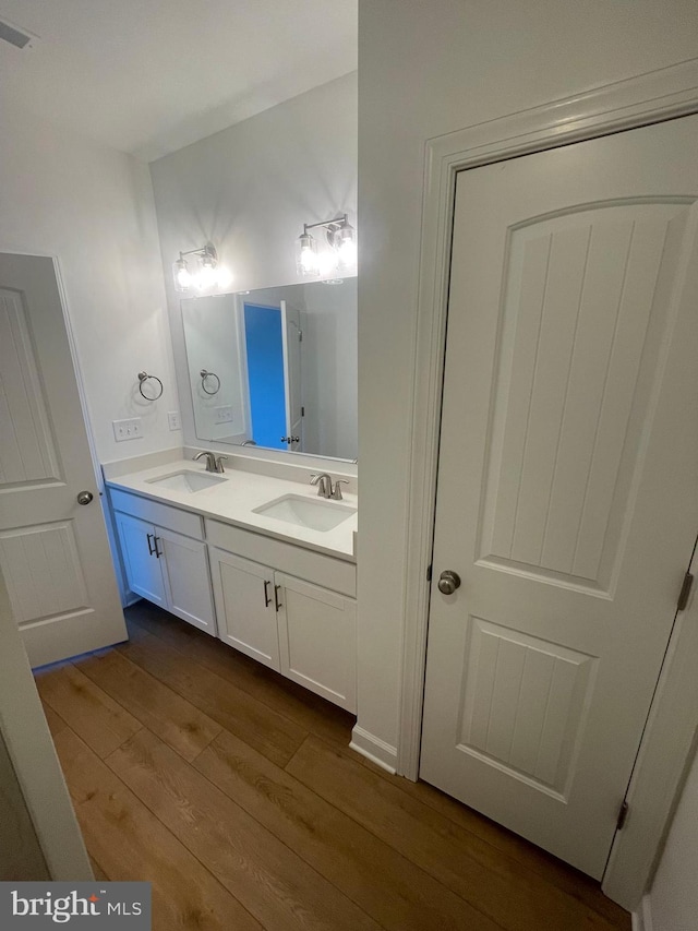 bathroom with double vanity, wood finished floors, a sink, and visible vents