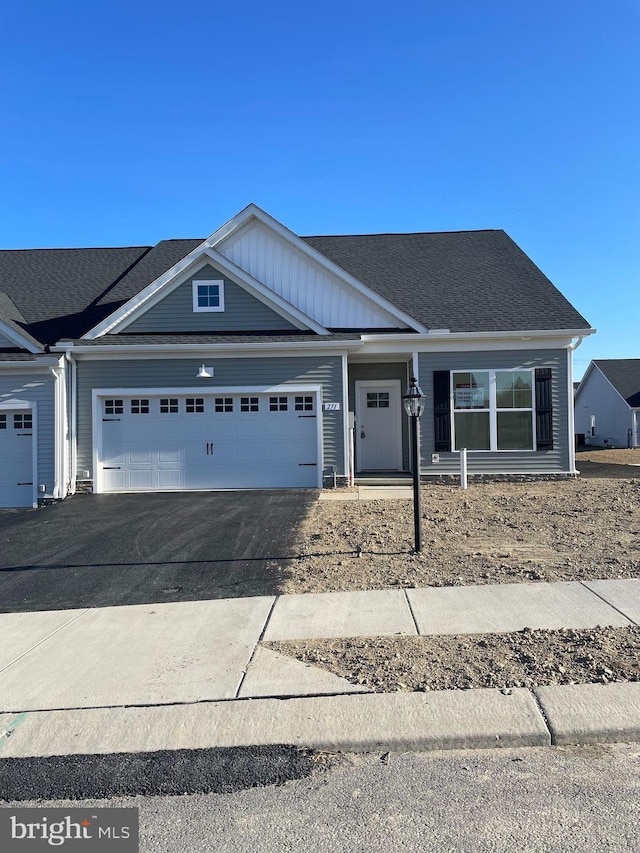 view of front of property with driveway, roof with shingles, and an attached garage