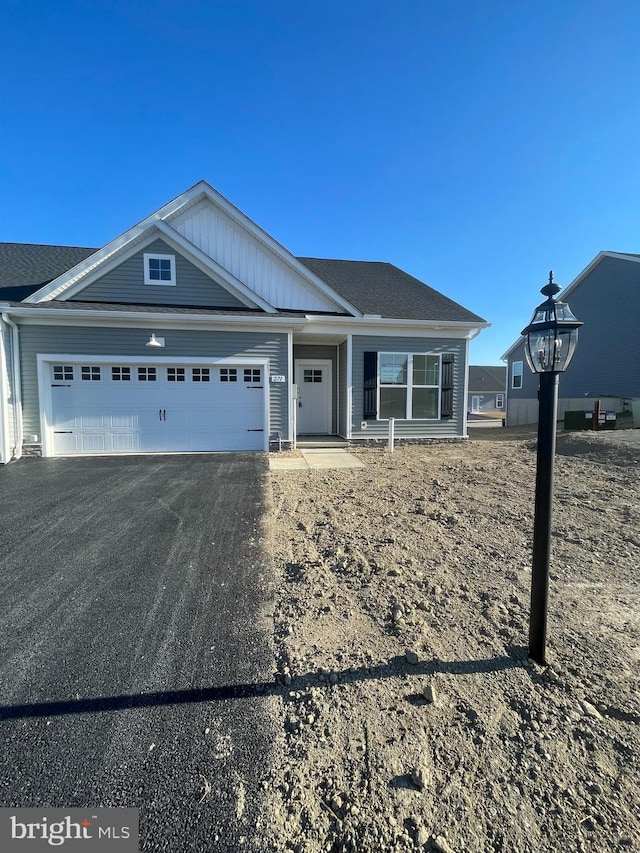 view of front facade featuring an attached garage, driveway, and a shingled roof