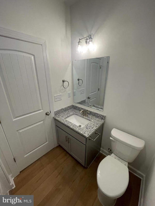 bathroom with vanity, toilet, and wood finished floors