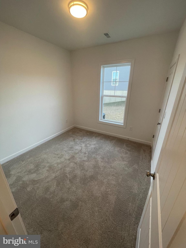 empty room featuring carpet, visible vents, and baseboards