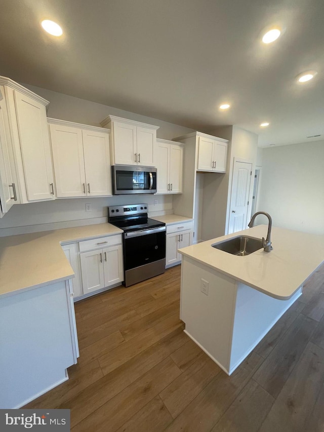 kitchen with dark wood finished floors, recessed lighting, appliances with stainless steel finishes, white cabinetry, and a sink