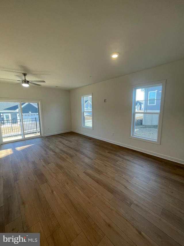 spare room featuring dark wood-style floors, a wealth of natural light, and baseboards