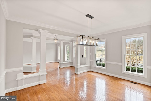 unfurnished dining area featuring crown molding, hardwood / wood-style floors, visible vents, and ornate columns