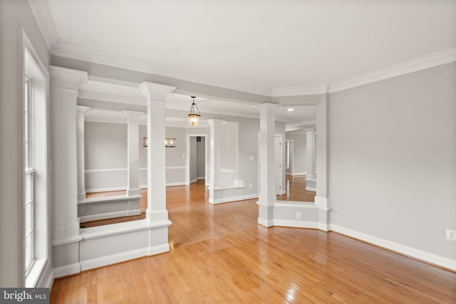 spare room featuring baseboards, crown molding, light wood finished floors, and ornate columns