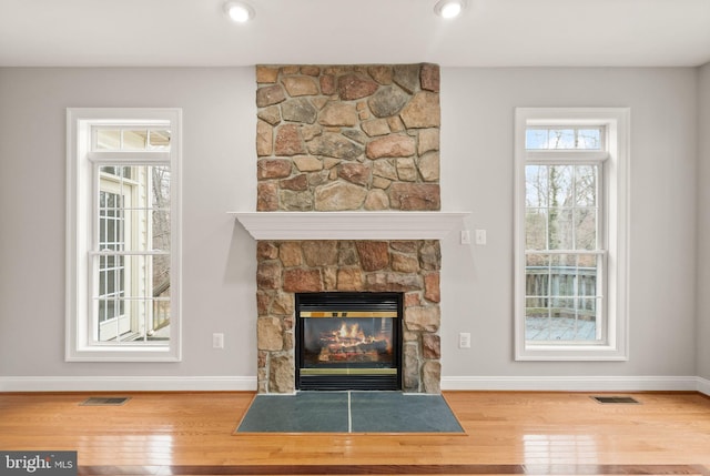 unfurnished living room featuring plenty of natural light, a fireplace, and wood finished floors