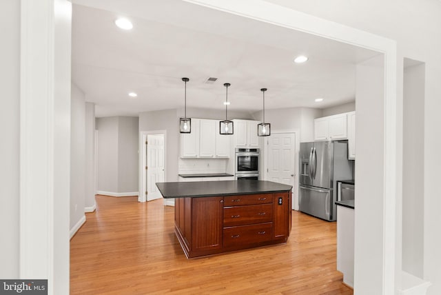 kitchen featuring stainless steel appliances, dark countertops, visible vents, light wood-style flooring, and white cabinetry