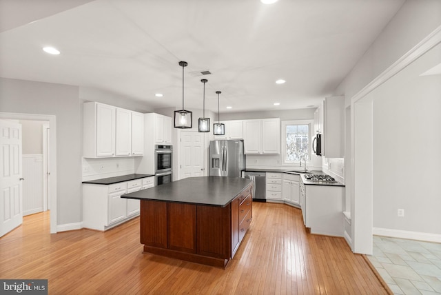 kitchen featuring stainless steel appliances, dark countertops, visible vents, light wood-style floors, and white cabinetry