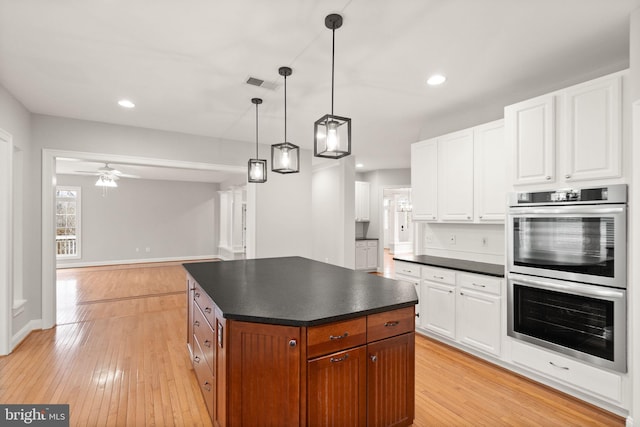 kitchen featuring double oven, dark countertops, visible vents, and light wood-style flooring