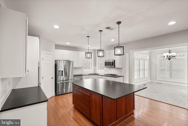 kitchen featuring stainless steel appliances, dark countertops, visible vents, and light wood-style floors