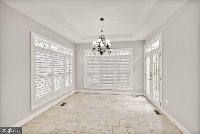 unfurnished dining area featuring a notable chandelier, visible vents, a tray ceiling, and baseboards