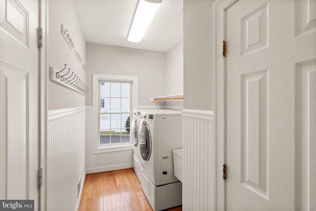 laundry area featuring laundry area, wainscoting, light wood-style flooring, and washer and dryer