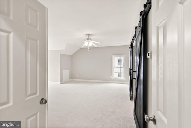 bonus room with ceiling fan, light colored carpet, vaulted ceiling, and a barn door