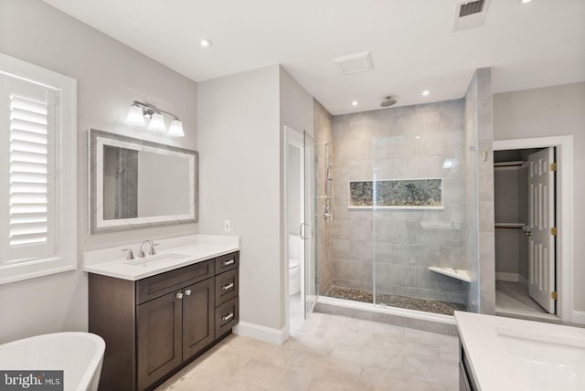 bathroom featuring visible vents, vanity, baseboards, a soaking tub, and a shower stall