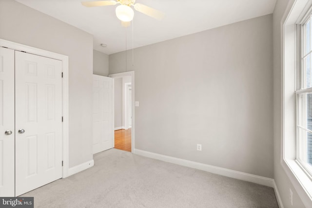 unfurnished bedroom featuring carpet, baseboards, ceiling fan, and a closet