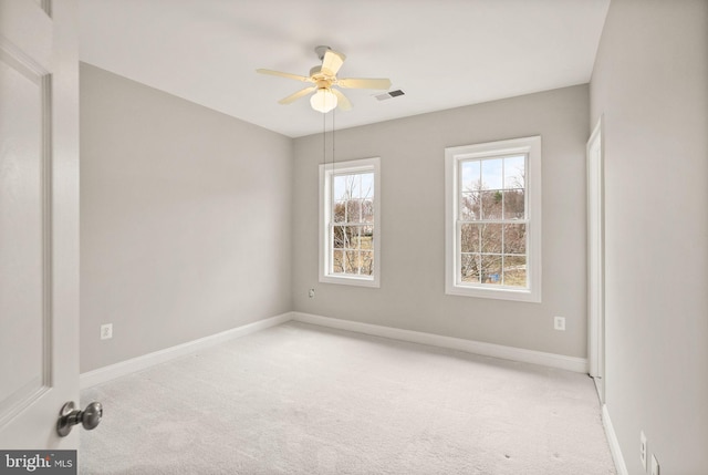 empty room with light carpet, baseboards, visible vents, and a ceiling fan