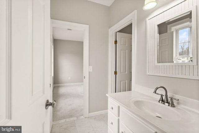 bathroom with marble finish floor, vanity, and baseboards