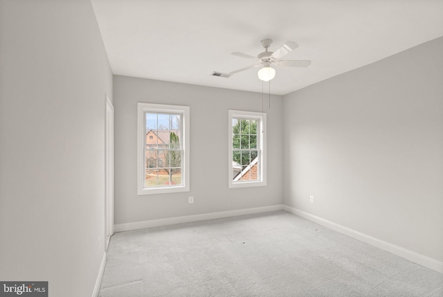 carpeted spare room featuring ceiling fan, visible vents, and baseboards