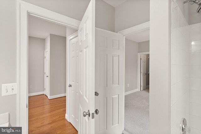 corridor featuring light wood-type flooring and baseboards