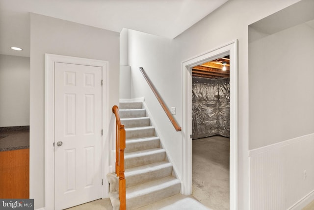 stairs featuring carpet floors and wainscoting