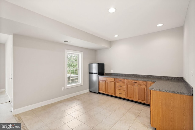 kitchen featuring dark countertops, recessed lighting, visible vents, freestanding refrigerator, and baseboards