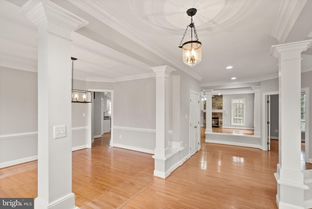 entryway with light wood finished floors, decorative columns, a fireplace, and crown molding