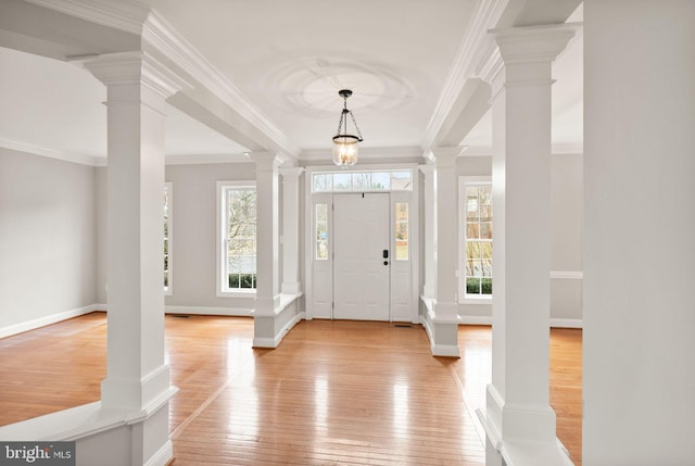 foyer with light wood-style flooring, decorative columns, and a healthy amount of sunlight