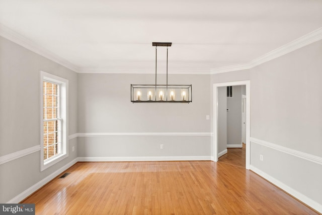 unfurnished room featuring a notable chandelier, visible vents, light wood-style floors, ornamental molding, and baseboards