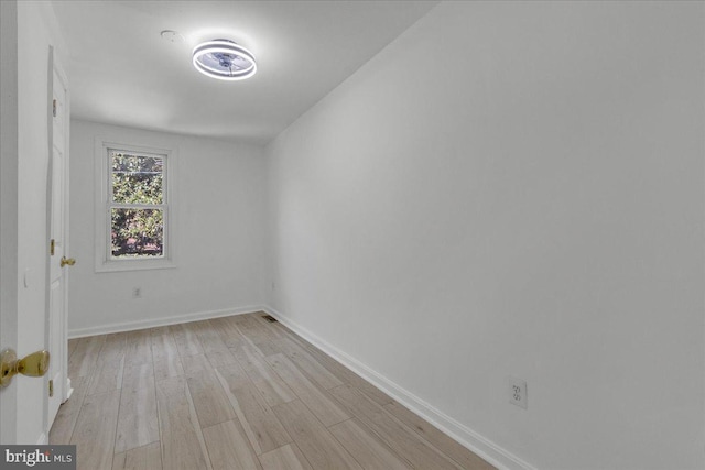 empty room featuring light wood-type flooring and baseboards