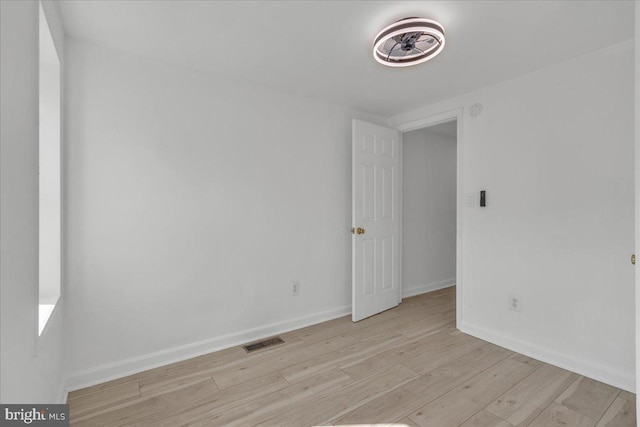 unfurnished room with light wood finished floors, visible vents, and baseboards