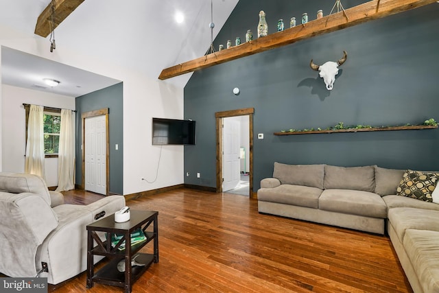 living area featuring a towering ceiling, baseboards, and wood finished floors