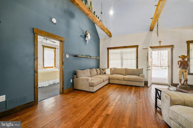 living room with a towering ceiling, visible vents, baseboards, beam ceiling, and hardwood / wood-style floors