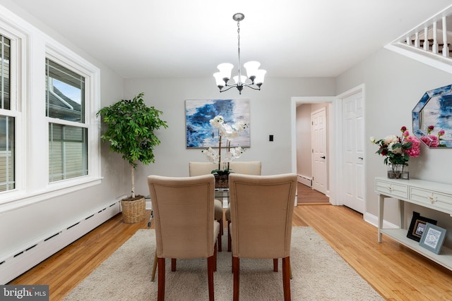 dining room featuring baseboard heating, light wood-style flooring, and an inviting chandelier