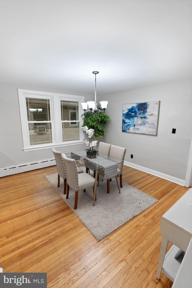 dining room featuring a notable chandelier, baseboards, baseboard heating, and wood finished floors