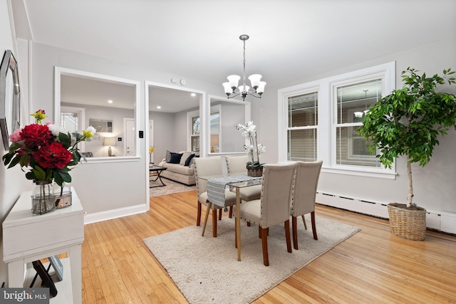 dining area with a baseboard heating unit, a wealth of natural light, an inviting chandelier, and wood finished floors