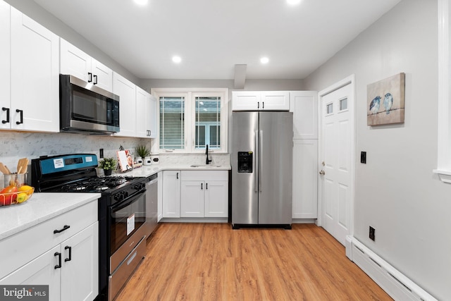 kitchen featuring stainless steel appliances, light countertops, a baseboard heating unit, white cabinetry, and a sink